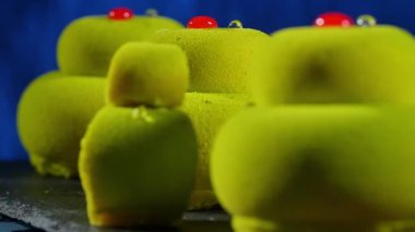 Arka plan koyu mavi, beyaz tabak üzerinde üç yeşil kek yakın çekim