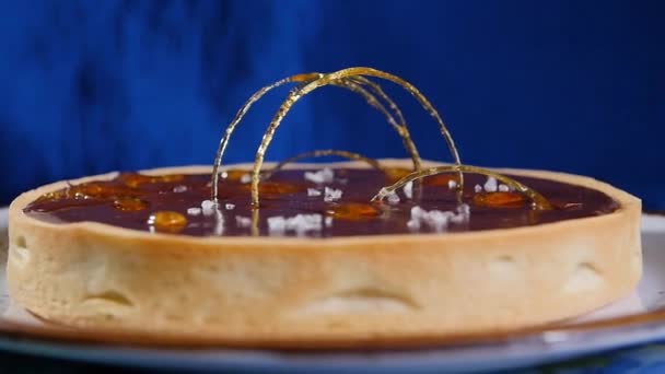 Gâteau au chocolat contemporain décoré de caramel jaune, sur fond bleu foncé . — Video