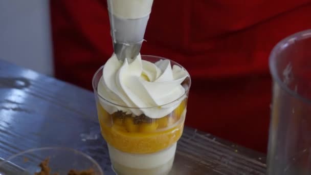 Kocken lägger vispad grädde i dessert i glas. Närbild på en utsökt hemmagjord milkshake lägga lite grädde på toppen — Stockvideo
