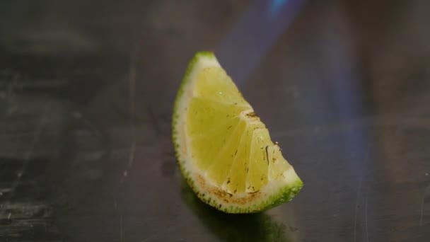 Chef burns slise of lime. Set fire to the slice of lime, lyme. Slice of lime and fire. Blaze on a part of lime with metal background — Stock Video