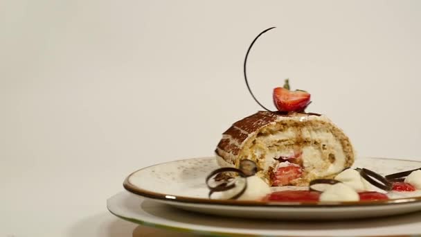 Pohled shora jahodový cheesecake na dřevěný stůl. Kus čokoládového dortu s jahodou zdobí na vrcholu. Vlhký tvarohový koláč s čerstvou jahodou na vrcholu a jahoda — Stock video