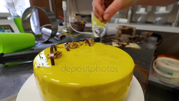 Mousse di torta di miele con una glassa liscia. Torta gialla. Spruzzando noci su una torta gialla — Video Stock