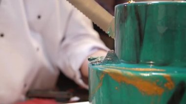 Pasta şefi pasta uzun bir bıçak ile kesmek. Turkuaz bir pasta kesti. Pasta şefi pasta kesme