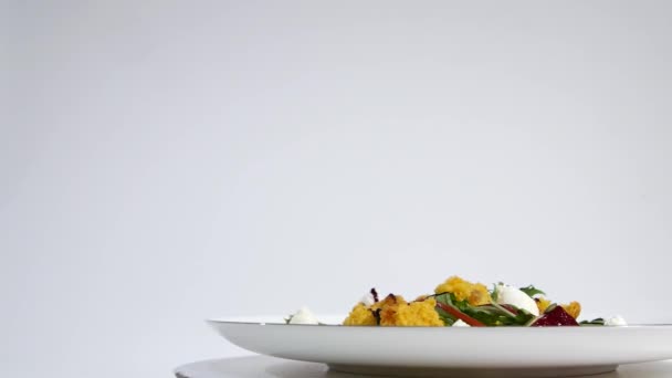 Итальянский салат жареной свеклы. Салат из жареной свеклы с козьим сыром и кедровыми орехами на белом блюде изолирован на белом фоне. Tagliatelle со свеклой и сыром на тарелке, мягкий фокус — стоковое видео