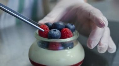 Ev yapımı yoğurt bir cam kavanoza yaban mersini ile. El koyarak çilekli yoğurt, yakın çekim.