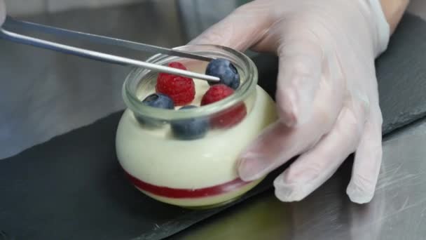 Yaourt maison aux myrtilles dans un bocal en verre. Main mettant la fraise dans le yaourt, gros plan . — Video