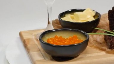 Doğranmış tereyağı, havyar, siyah ekmek. Kaşık ile kırmızı havyar kase dilimlenmiş ekmek, tereyağı ve otlar beyaz arka plan üzerinde hizmet verdi. Kepekli ekmek, tereyağı ve kırmızı havyar, beyaz arka plan