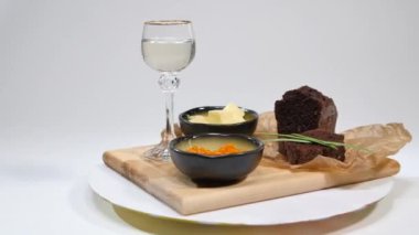 Fesleğen ve Studio ekmek üzerine tereyağı ile taze kırmızı havyar. Şarap gözlük arka plan üzerinde kırmızı havyar ile yetiştirilmiş. Buz ve küçük aperatifler tereyağı ve kırmızı havyar ile soğuk Rus votka