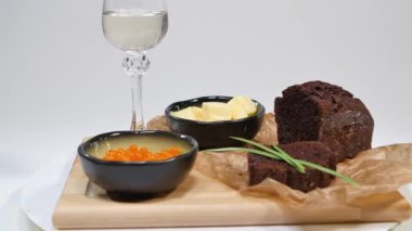 Fesleğen ve Studio ekmek üzerine tereyağı ile taze kırmızı havyar. Şarap gözlük arka plan üzerinde kırmızı havyar ile yetiştirilmiş. Buz ve küçük aperatifler tereyağı ve kırmızı havyar ile soğuk Rus votka