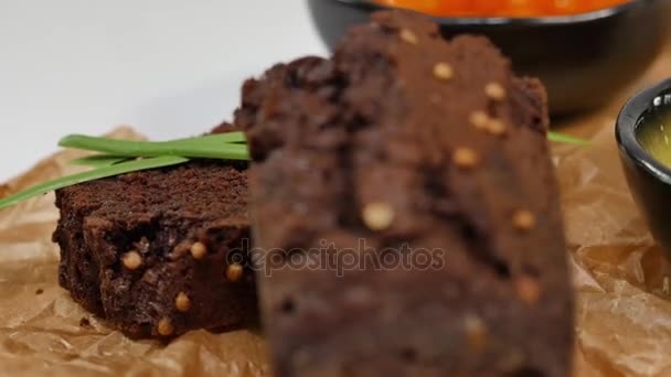 Gewürfelte Butter, Kaviar, Schwarzbrot. Schüssel mit rotem Kaviar mit Löffel, serviert mit geschnittenem Brot, Butter und Kräutern auf weißem Hintergrund. Vollkornbrot, Butter und roter Kaviar, weißer Hintergrund — Stockvideo