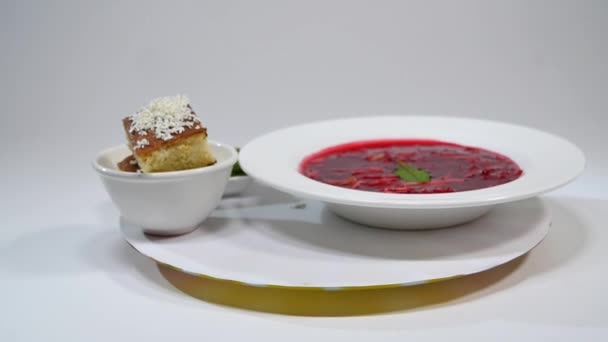 Borsch plaka ile tahta kaşık ve siyah ekmek üzerinde beyaz izole. Sebze ve et kırmızı pancar çorbası veya ekşi krema ile borsch. ekmek, yeşil soğan, maydanoz. — Stok video