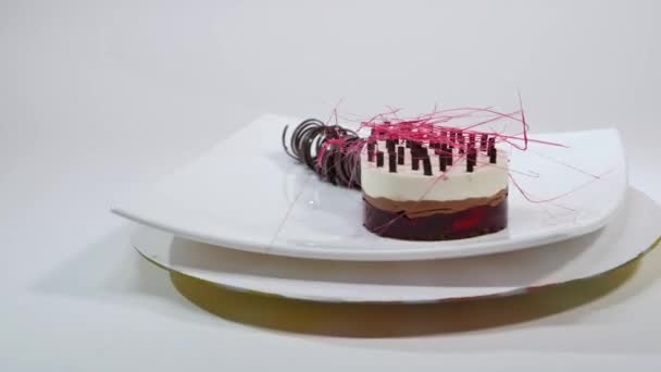 Bir plaka üzerinde üç kat kremalı pasta. Kremalı pasta çikolata kırıntıları ve çikolata saman ile dekore edilmiş üç kat ile — Stok video