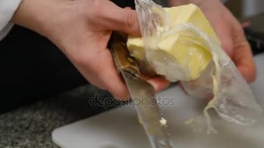 Şef tereyağı hazırlama kek için büyük bir parça keser. Pasta tereyağı bir bıçak ile kesmek.