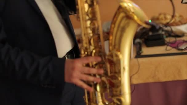 Saksofonista w smokingu odtwarza muzykę na saksofon. Muzyk gra saksofon wydajność na koncercie. Noc jazzu — Wideo stockowe