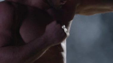 Savaşçı siluet. Yakışıklı atletik adam boks standında karanlık bir arka plan üzerinde. Kas genç adam boks eldivenleri ve şort farklı hareketleri ve grevler gösterir