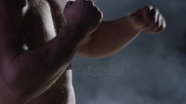 Savaşçı siluet. Yakışıklı atletik adam boks standında karanlık bir arka plan üzerinde. Kas genç adam boks eldivenleri ve şort farklı hareketleri ve grevler gösterir