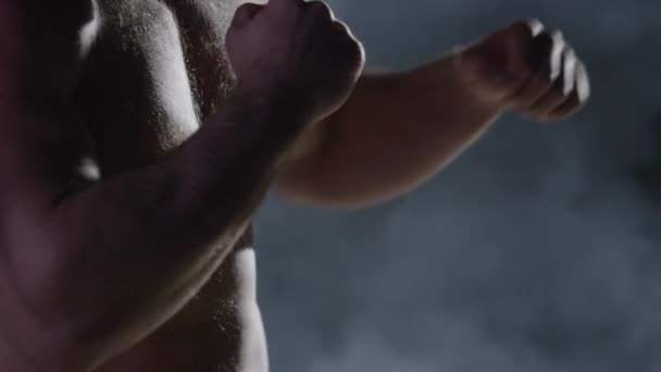 Силуэт истребителя. Симпатичный спортсмен в боксе стоит на тёмном фоне. Мускулистый молодой человек в боксёрских перчатках и шортах показывает различные движения и удары — стоковое видео