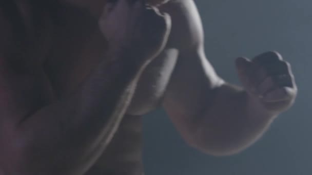 Kämpfersilhouette. Der gut aussehende, athletische Mann im Boxsport steht auf dunklem Hintergrund. muskulöser junger Mann in Boxhandschuhen und kurzen Hosen zeigt die verschiedenen Bewegungen und Schläge — Stockvideo