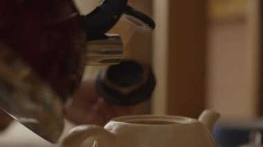 Kadın bir çay poşeti fincan ve demlemek çayına içine kaynar su dökülen. Kadın sıcak su ile çay çaydanlık içine dökülen