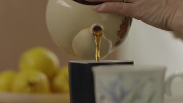 Womans ręka wlać herbatę z czajniczek do szkła — Wideo stockowe