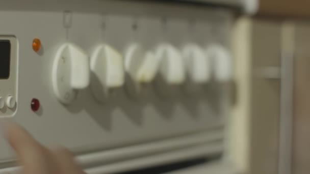 Vrouwelijke hand draaien op witte keuken gasstel. Vrouw zet het fornuis in de keuken close-up — Stockvideo