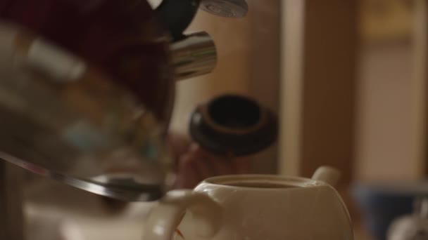 La mujer vierte agua hirviendo en la taza y prepara té en una bolsa de té. La mujer vierte agua caliente en la tetera con té — Vídeos de Stock