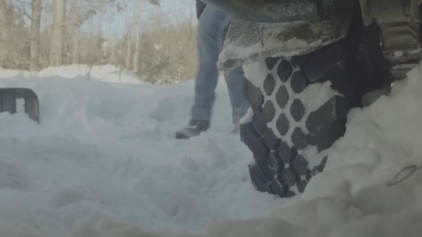 Крупним планом людина копає застряг у сніговій машині. Чоловік вириває сніг з машини — стокове відео