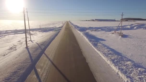 Strade aeree. Suv guida nella bianca foresta sempreverde innevata su strada asfaltata scivolosa. Veduta aerea della strada e dei campi in inverno — Video Stock