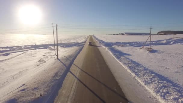 Luftwege. Geländewagen fahren im weißen, schneebedeckten immergrünen Wald auf rutschiger Asphaltstraße. Luftaufnahme der Straße und der Felder im Winter — Stockvideo