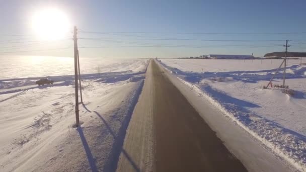 空中道路。Suv の滑りやすいアスファルトの道路上の白い雪に覆われた林運転。道と冬のフィールドの空撮 — ストック動画