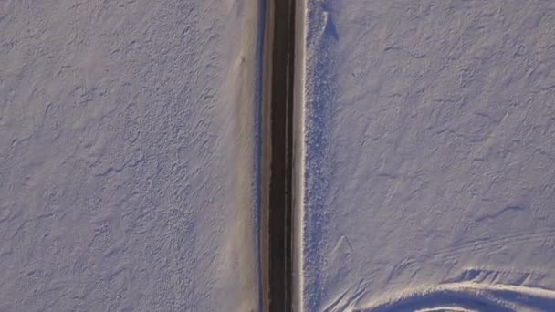 Aerial view of snowy fields and road. SUV driving on winter roads through the snowy field. Aerial view of the car driving on road and the fields in the winter — Stock Video