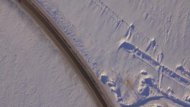 Vista aérea de los campos nevados y la carretera. SUV conduciendo en carreteras de invierno a través del campo cubierto de nieve. Vista aérea del coche que conduce por carretera y los campos en el invierno — Vídeos de Stock