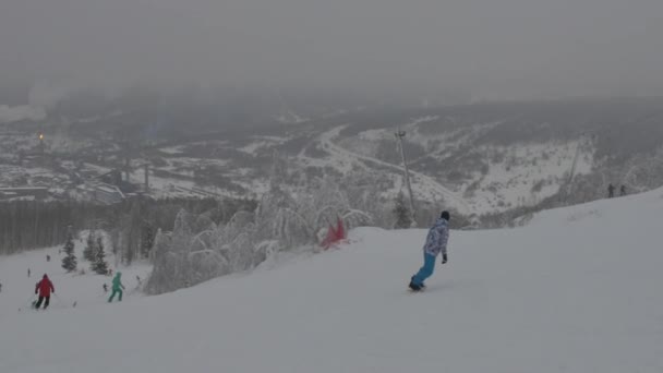 Vinter bergen panorama. Skidåkare och snowboardåkare silhuett högt i bergen. skidåkare, snöiga kullar och solen framfördem. Några av friåkare på kullen — Stockvideo