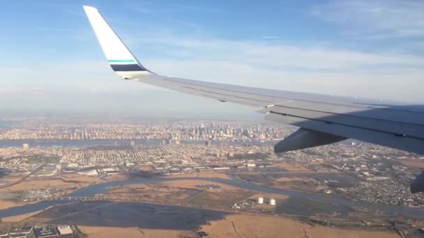 Blick durch das Fenster eines Flugzeugs, Flugzeugs oder Flugzeugflügels. Blick aus dem Flugzeugfenster bei Landung oder Start über das Stadtgebiet — Stockvideo