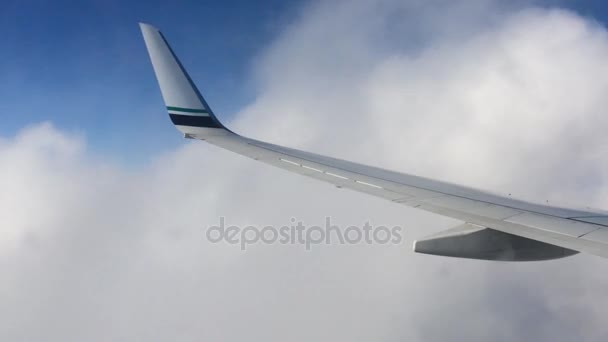 Ala di un aeroplano che vola sopra le nuvole. La gente guarda il cielo dal finestrino dell'aereo, usando il trasporto aereo per viaggiare — Video Stock