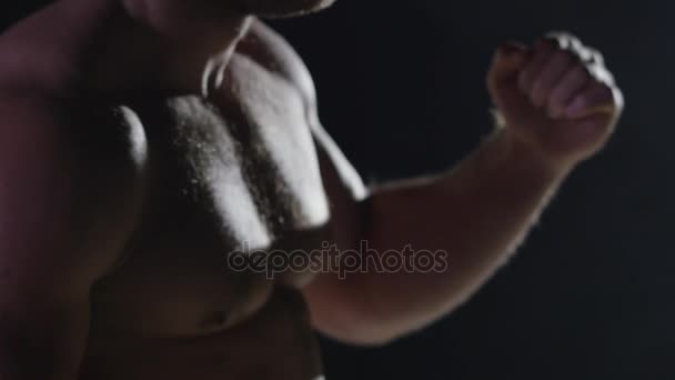Combatiente agresivo entrenando boxeo de sombras en el gimnasio lanzando golpe vicioso sobre fondo negro. Kickbox boxeador haciendo sombra de boxeo — Vídeo de stock