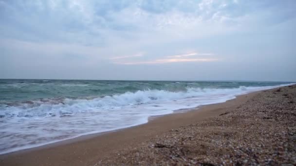 Spray de onda salpicar sobre a praia no mar azul. Onda suave na praia de areia. Pôr do sol — Vídeo de Stock