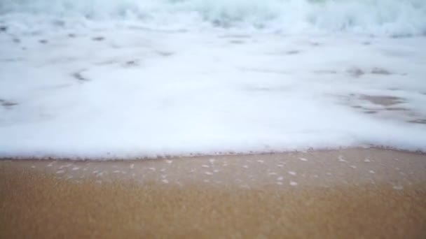 Spray de onda salpicar sobre a praia no mar azul. Onda suave na praia de areia. Pôr do sol — Vídeo de Stock