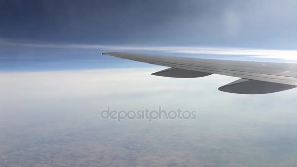 View from a plane window on the wing and the landscape below it. Wing of an airplane flying above the clouds — Stock Video