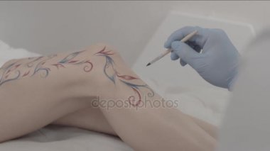 Birisine bir sanatçı el çizim geçici dövme bacak yakın çekim. Genç kadın vücut sanatı. Ressam bir süsleme ve dekorasyon bacağı üzerinde yapma