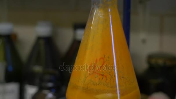 Laboratorium naukowe szkła stożkowej Erlenmeyera wypełnione bursztynu pomarańczowy płynów chemicznych dla chemii eksperyment w laboratorium badań naukowych. Chemicznych cieczy w kolbie z odbicia — Wideo stockowe