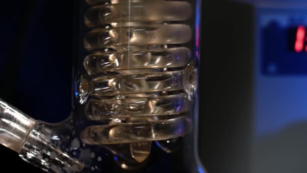 Espiral de cristal. Tubo de vidro espiral com água de perto. Tubo espiral de vidro do condensador de refluxo com água corrente. filtração de fluidos no experimento laboratorial — Vídeo de Stock