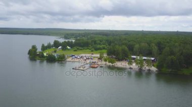 Göl kıyı liman hava görünümünü. Güzel hava görünümünü yukarıda. Çarpıcı Plajı manzaralı pier yürüyüş insanlarla. Plaj ve ormanı havadan görünümü