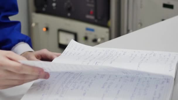 Hand blad genom notebook. vetenskap-konceptet. Hand med bläddrade vetenskap anteckningsbok på bakgrunden lab. — Stockvideo