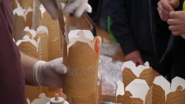 Handen zetten take-out voedsel container, close-up. Levering van voedsel. Close Up van chef-kok serveert één gedeelte van het roer gebakken noedels in Chinese nemen uit doos — Stockvideo