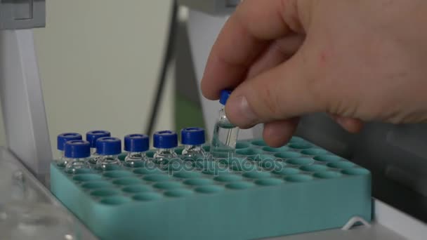 Scientist holds a chemical sample bottle. Doctor hand in medical glove with clinical chemistry samples putting them to centrifuge. People hand holding a test tube vial sets for analysis. — Stock Video