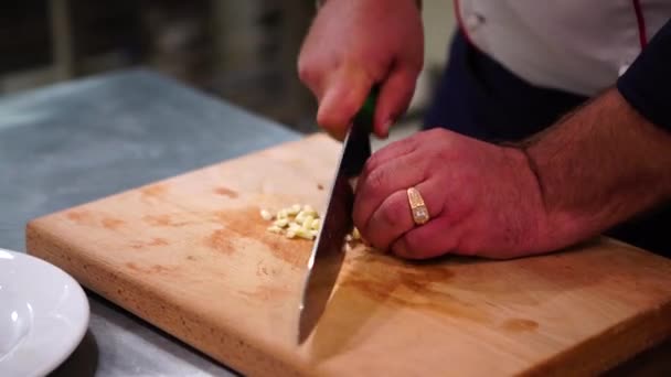 Uno chef che taglia aglio su un tagliere. Un uomo che taglia cibo. Uomo che taglia l'aglio con il coltello — Video Stock