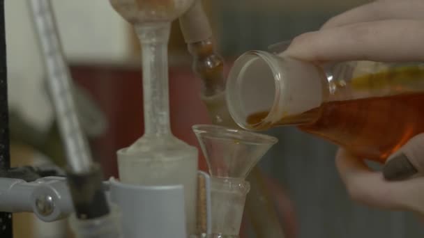 Chemische glas met groene vloeistof gegoten in een rode onder de trechters. Hand voegt rode gemengde vloeistof in de kolf. een scheikundige of medisch onderzoeker toevoegt chemische stoffen aan een conische kolf van voor chemische — Stockvideo