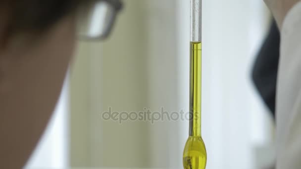Close-up of glass tube with blue fluid in scientist hand during medical test. scientists hand holding a test-tube with green chemical liquid. Scientist fingers holding a glass test tube in a research — Stock Video
