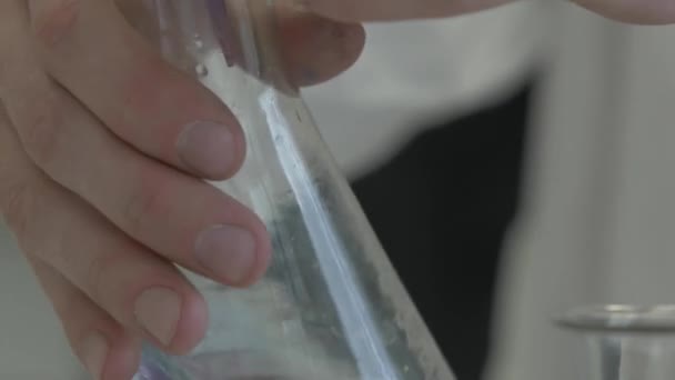 Mano vertiendo químicos líquidos en el frasco. Trabajador de laboratorio mezclando químicos — Vídeo de stock